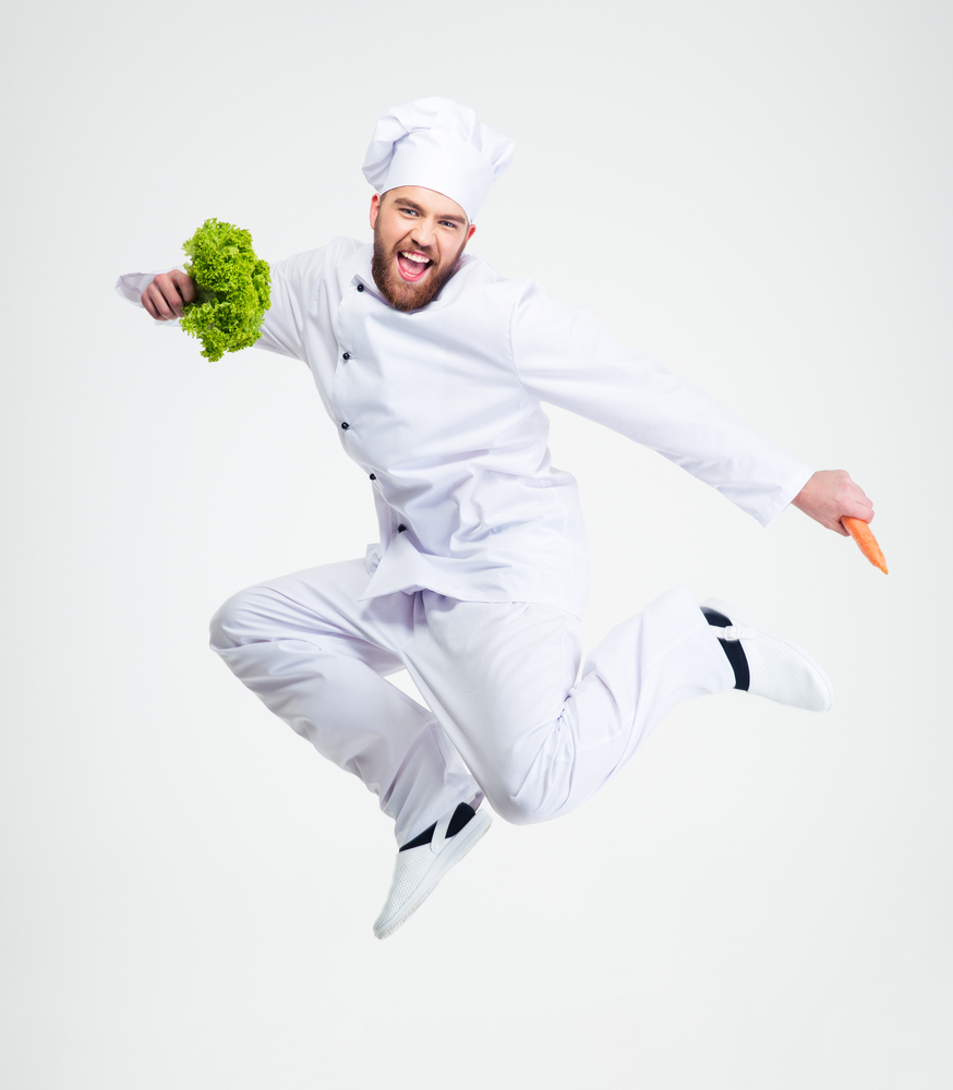 Full length portrait of a cheerful chef cook dancing isolated on a white background