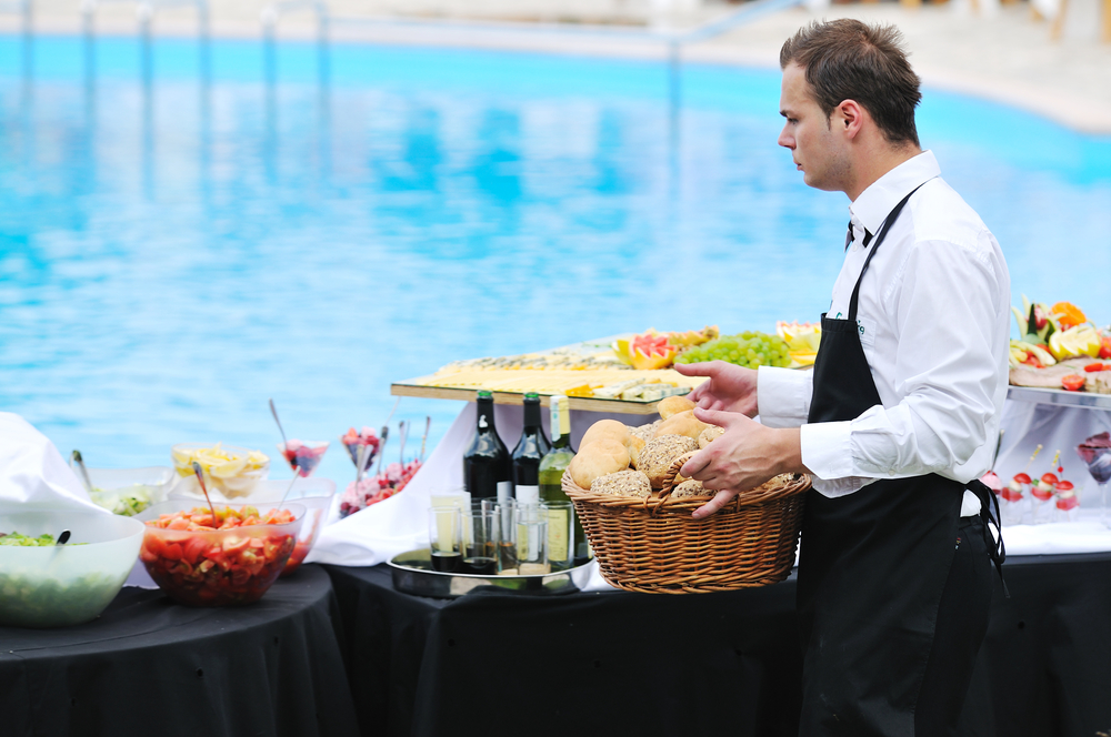 young people serving food on buffet wedding seminar or conference outdoor party with fresh food and drink